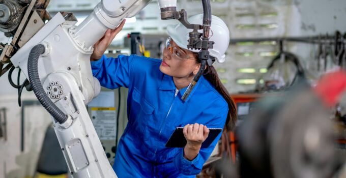Asian factory worker woman hold tablet and maintenance with check part of robot