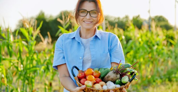Middle-aged woman gardener farmer with basket of ripe vegetables