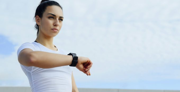 Athlete woman runner looking at the time on the clock