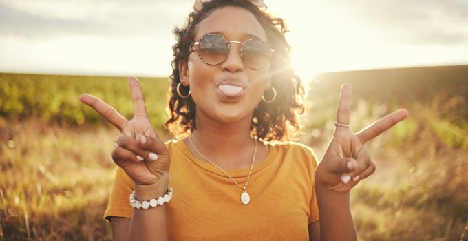 Nature, freedom and peace hand sign by woman at sunset in the countryside, happy and content while