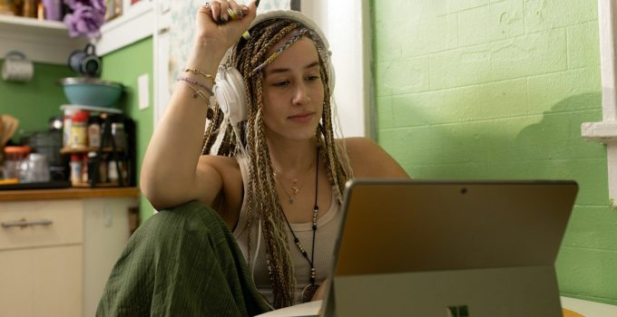a woman with dreadlocks sitting in front of a laptop computer
