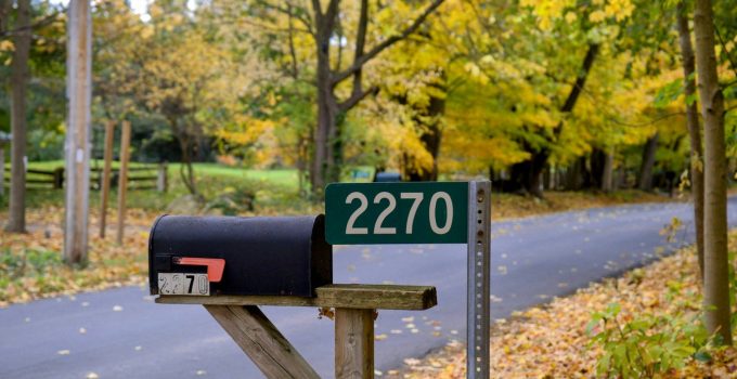 Black mailbox marked 2270 on a post beside a rural road with autumn trees