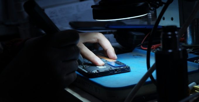 Close-up of hands repairing an open smartphone