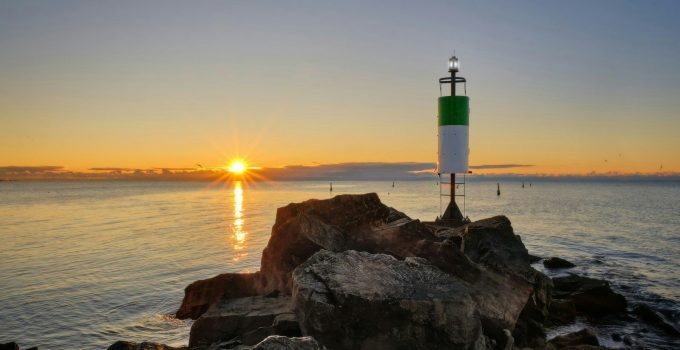 Sunrise over the ocean with a lighthouse on rocks